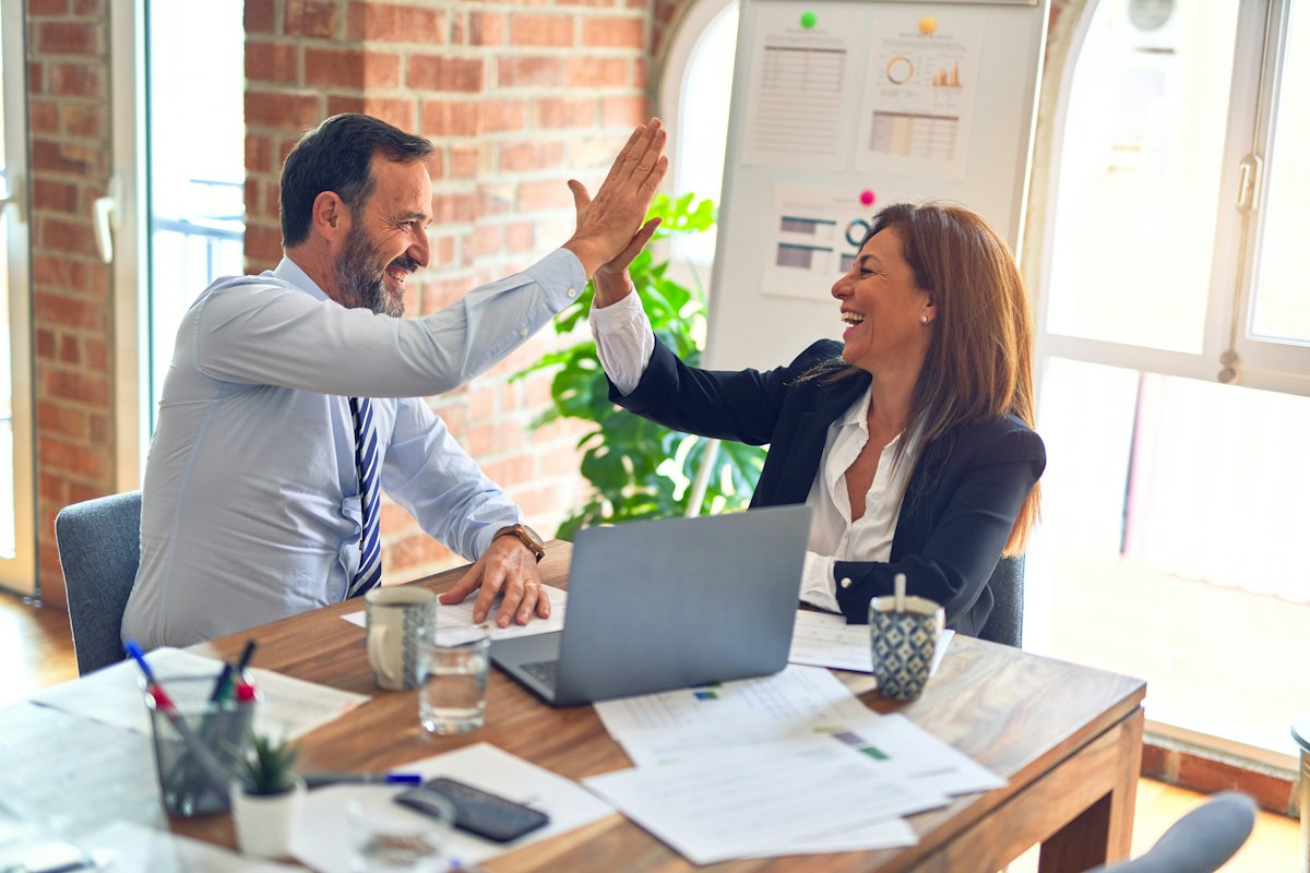 Two colleagues celebrating with a high five at the office